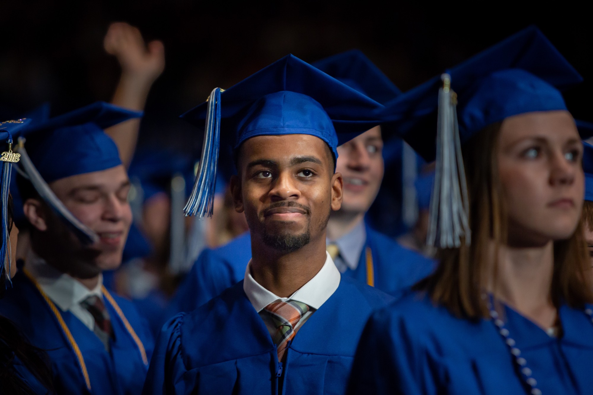 Student smiling proudly at graduation wearing a blue Academic Cap